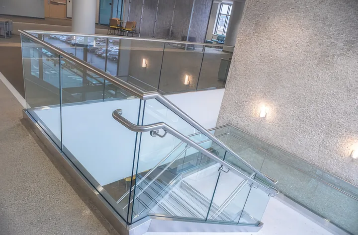 Glass railing with a steel top rail around an open stair
